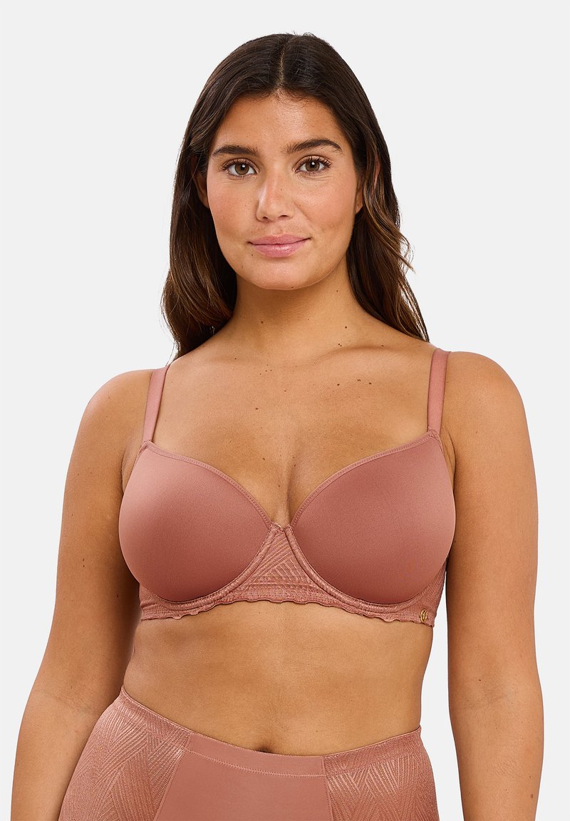 Soutien-gorge rose clair avec des bonnets moulés, des garnitures en dentelle et des bretelles réglables. Présente un motif géométrique sur la bande. Texture lisse.