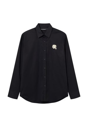 Zwart overhemd met lange mouwen en knopen, met een kleine witte afbeelding van een gestileerd gezicht met een bril op de linkerborst.
