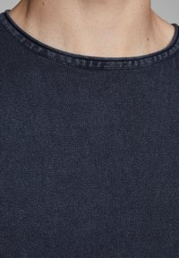 T-shirt bleu marine à col rond avec un col côtelé et une texture lisse, mettant en valeur le tricot dense du tissu et son léger éclat.