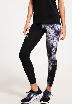 Leggings with black base and patterned gray panel featuring abstract designs. Stretchy fabric, fitted shape, complemented by accent seams.