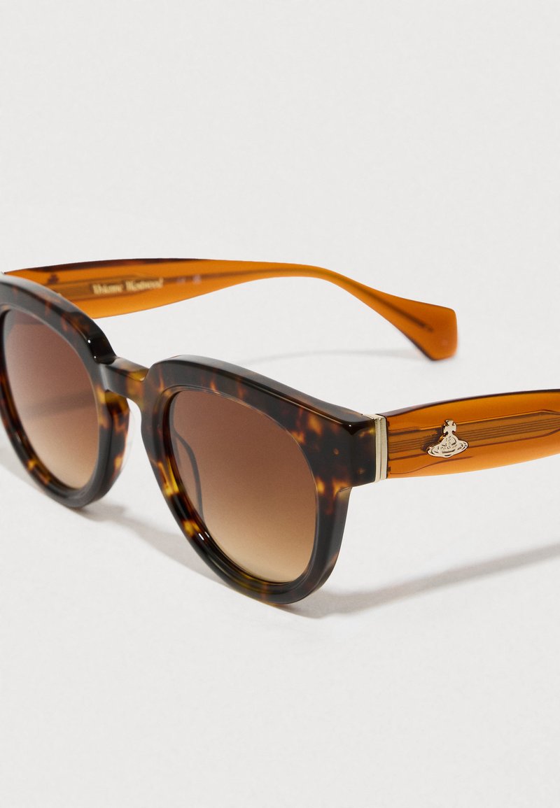 Skildpadde-sunglasses med en kraftig ramme, gradient brune linser og orange sider med et lille metallic-emblem.