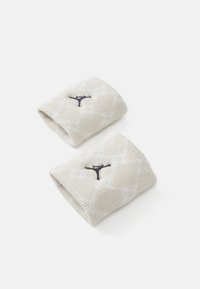 Dva svijetlosmeđa remena za zapešća napravljena od rebrastog materijala, s tamnosivim logotipom. Tekstura je meka s suptilnim, uzorcima.