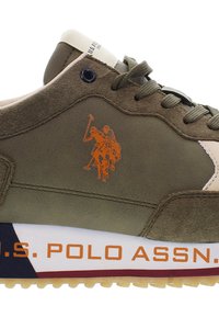 Olivgrön sneaker med mocka och syntetmaterial, med orange polo-logotyp, beige accenter och vit sula med varumärkestext.