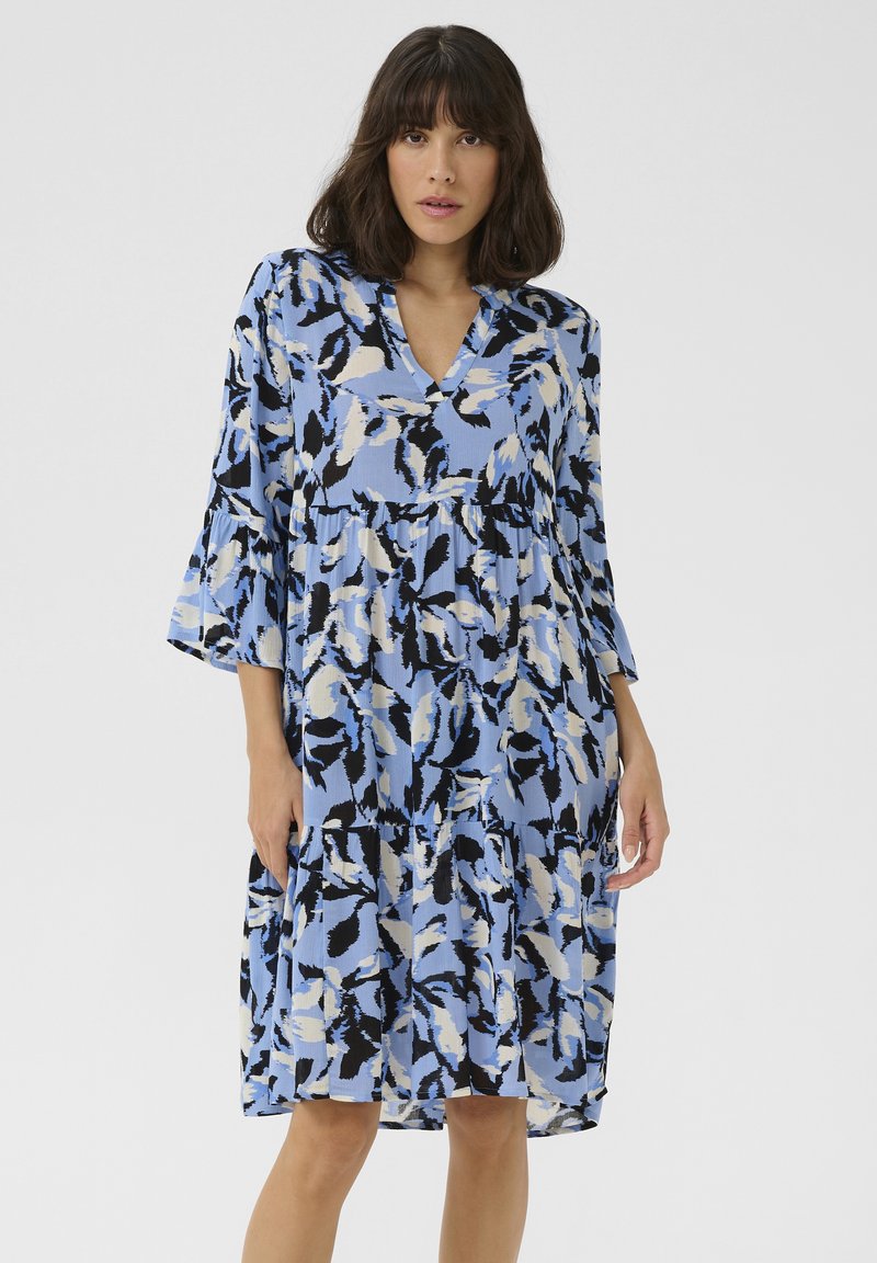 Robe à imprimé floral dans des tons de bleu clair, noir et crème. Elle présente un col en V, des manches cloche trois-quarts et une jupe à volants.