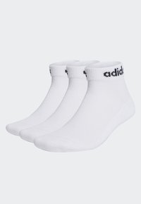 Chaussettes blanches jusqu'à la cheville en mélange de coton, avec un bord côtelé et le logo "adidas" noir sur la bande. Trois paires présentées ensemble.