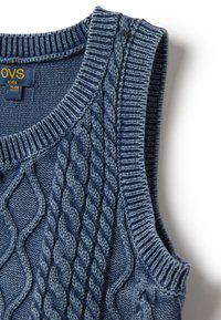 Blau gestrickter ärmelloser Pullover mit Zopfmuster, geripptem Halsausschnitt und Armöffnungen. Weiche Textur, geeignet für Kinder. Markenlabel sichtbar.