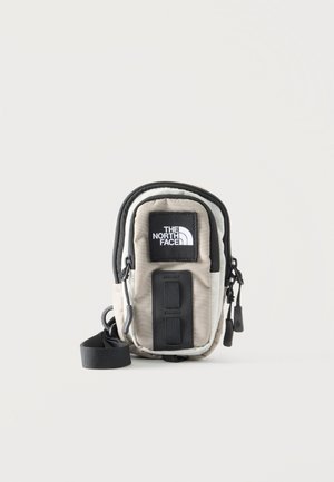 Bolso pequeño North Face beige y negro para colgar al hombro con parche de logotipo delantero, dos compartimentos con cremallera y correa de hombro ajustable.