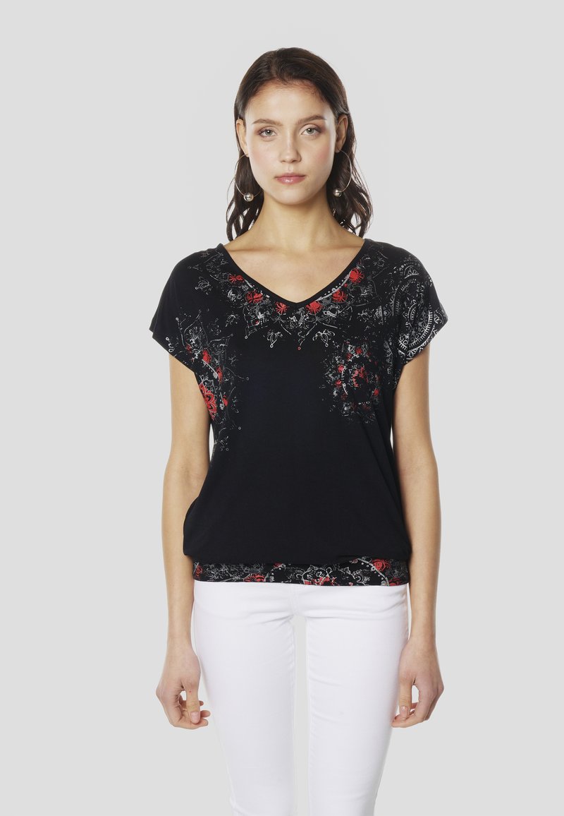 Schwarzes kurzärmeliges Oberteil mit V-Ausschnitt, das rote Blumenmuster und filigrane silberne Muster entlang der Brust und des Saums zeigt. Hergestellt aus weichem Stoff.