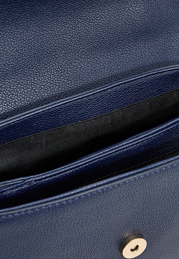 Portefeuille en cuir texturé bleu marine avec des compartiments visibles, doté d'une fermeture à pression dorée et d'un revêtement en tissu noir lisse.