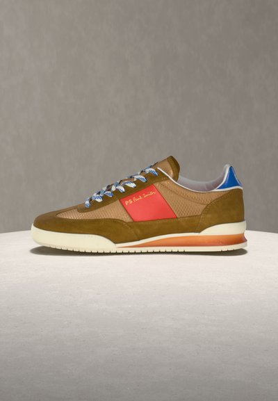 Καθημερινό αθλητικό παπούτσι με καφέ σουέτ και διχτυωτό ύφασμα, κόκκινη πλαϊνή επιφάνεια με την επιγραφή «PS Paul Smith», λευκή σόλα, μπλε ταμπελάκι στη φτέρνα και μπλε-λευκά κορδόνια.