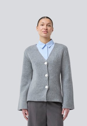 Lys grå strikket cardigan med lange ærmer og v-udskæring, der har tre hvide knapper og en glat tekstur. Bæres over en lys blå skjorte.