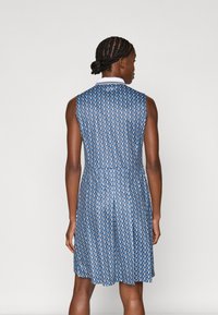 Zila piedurkņu kleita ar ģeometrisku rakstu, ar baltu apkakli un plisētu svārkiem, izgatavota no viegla auduma.