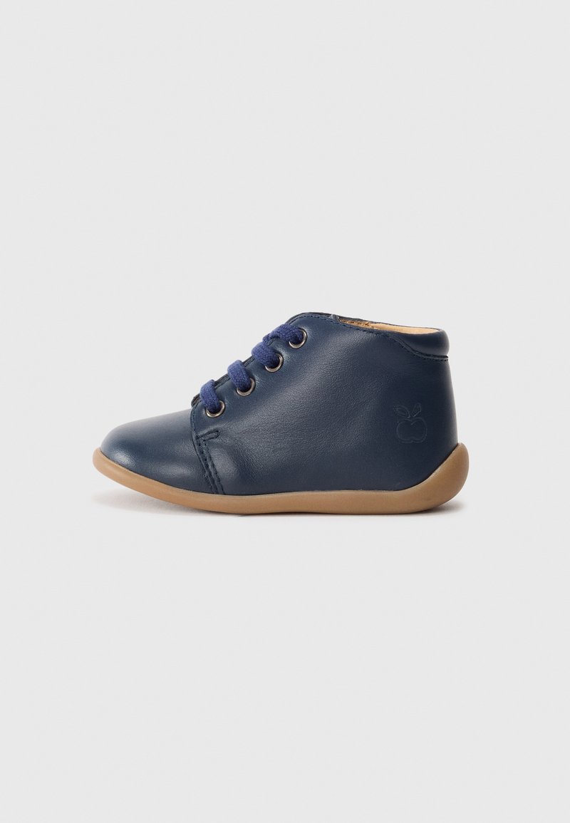 Chaussure en cuir marine pour tout-petit avec des lacets bleus, semelle flexible beige et logo pomme en relief sur le talon, présentée en profil latéral.