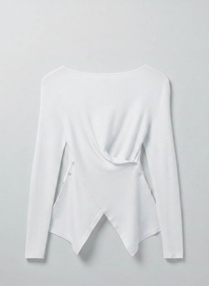 Άσπρο πλεκτό μακρυμάνικο τοπ με ασύμμετρο, επικαλυπτόμενο τελείωμα και λεπτομέρειες με κουμπιά στις πλευρές, σε μονόχρωμο φόντο.