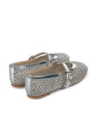 Ballerines argentées ornées, avec un bout rond, présentant une sangle et une surface texturée embellie de petits clous brillants. Semelle marron clair.