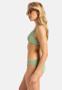 Ensemble de bikini vert avec un motif texturé comprenant un haut asymétrique à une épaule et un slip assorti, fabriqué en tissu extensible.