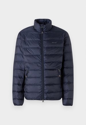 Navy blue puffer jacket with a zippered front, high collar, and horizontal stitching, featuring side pockets with zippers.