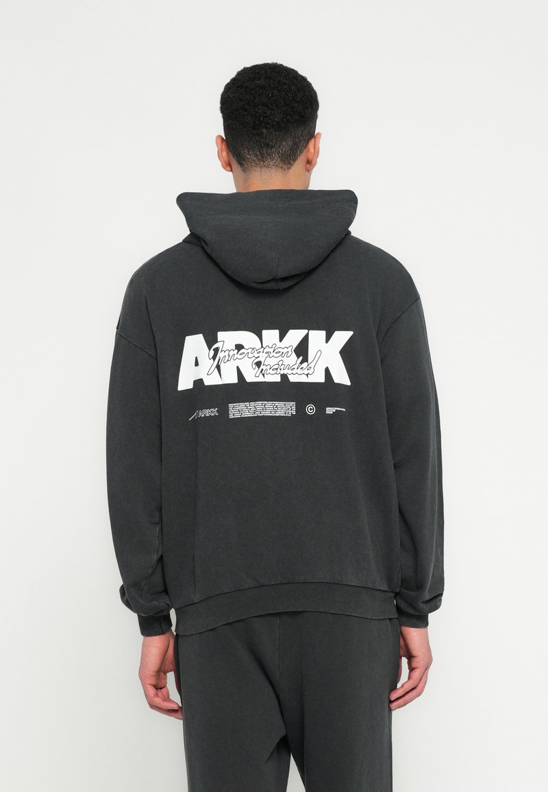 Sudadera de color gris oscuro, confeccionada en una mezcla de algodón y con un corte holgado, que presenta un gran estampado gráfico blanco y una capucha. Puños y dobladillo acanalados.