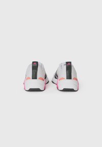 Scarpe da ginnastica grigie con accenti neri, dettagli rosa sul tallone e una suola testurizzata. Presentano un logo sul retro e un design in materiale sintetico.