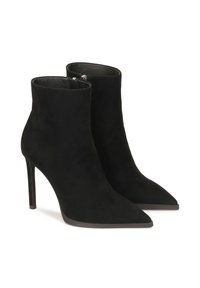 Botines de ante negro con puntas afiladas y tacones de aguja. Textura suave y diseño minimalista. Cremallera lateral para facilitar su uso.