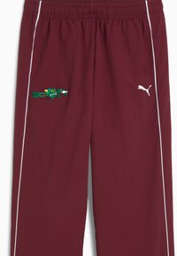Burgundowe spodnie sportowe z białymi paskami po bokach, z haftowanym wzorem krokodyla w kolorze zielonym i żółtym oraz białym logo Pumy. Elastyczny pasek w talii.