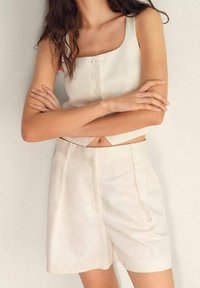 Krémový krátký top bez rukávů se čtvercovým výstřihem a detailem na knoflík, kombinovaný se shodnými tailored šortkami s bočními kapsami.