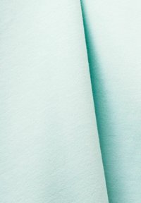 Plegados de tela turquesa claro con una textura suave, que exhiben una superficie lisa y un sutil patrón de tejido.