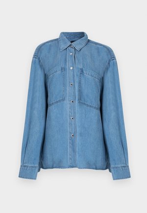 Blaues Denim-Hemd zum Knöpfen mit langen Ärmeln, zwei Brusttaschen vorne und einem klassischen Kragen, vor einem weißen Hintergrund dargestellt.