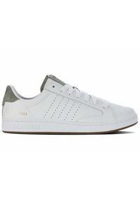 Basket en cuir blanc avec des accents en daim vert, design perforé sur les côtés, bout rond, semelle en caoutchouc plate et détails de logo doré.