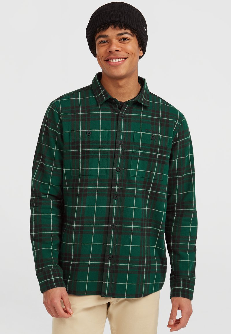 Grøn- og sort plaid flannel skjorte med knapper, som har to brystlommer og lange ærmer, båret med en sort strikket hat.
