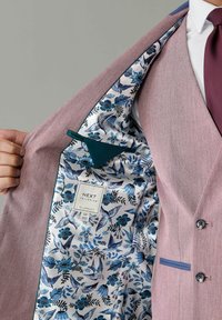 Rosa und grauer maßgeschneiderter Anzugjacke mit einem blumigen Futter in Blau und Weiß. Verfügt über ein Etikett und eine Tasche. Doppelte Knopfverschluss.