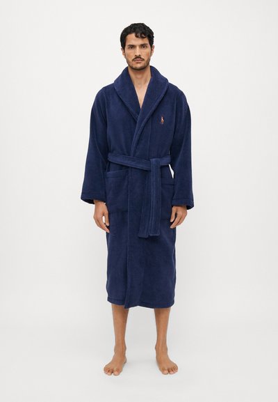 Accappatoio in spugna blu navy con colletto a scialle, tasche davanti e cintura da annodare. Texture morbida e design fino al ginocchio, adatto per il relax.