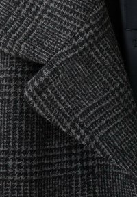 Abrigo de lana con patrón de pied de gallo en gris oscuro y negro, con detalles de tejido texturizado en las solapas.