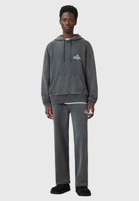 Grijze katoenen hoodie met een voorzak en een verstelbare koord. Gecombineerd met bijpassende broeken en zwarte instappers. Bevat logodetail.