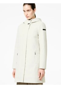 Giacca impermeabile beige chiaro con cappuccio, chiusura frontale con zip, tasche laterali con zip e un design elegante caratterizzato da un accento nero sul maniche.