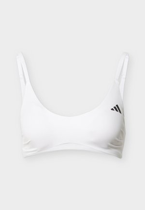 Valkoinen urheiluliivit, joissa on ohuet säädettävät olkaimet ja pieni musta Adidas-logo vasemmalla puolella, esitetty vaalealla yksinkertaisella taustalla.