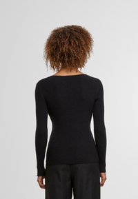 Schwarzer gerippter Pullover mit körperbetontem Design, langen Ärmeln und weitem Ausschnitt. Hergestellt aus strukturiertem Stoff, der ein dezentes Muster aufweist.