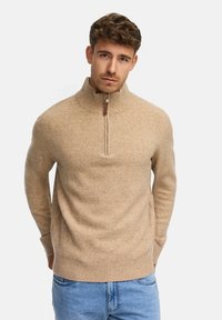 Beige gestrickter Pullover mit hohem Kragen und halber Reißverschluss. Mit gerippten Bündchen und Saum. Weiche Textur mit subtilen Melange-Muster.
