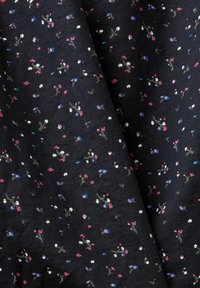 Tissu foncé avec un petit imprimé floral dispersé en rose, blanc, bleu et vert, présentant de délicates grappes de fleurs sur un fond texturé.