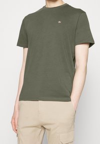 Olivengrøn bomulds-T-shirt med rund halsudskæring, korte ærmer og et lille broderet logo på brystet; glat tekstur, afslappet pasform.