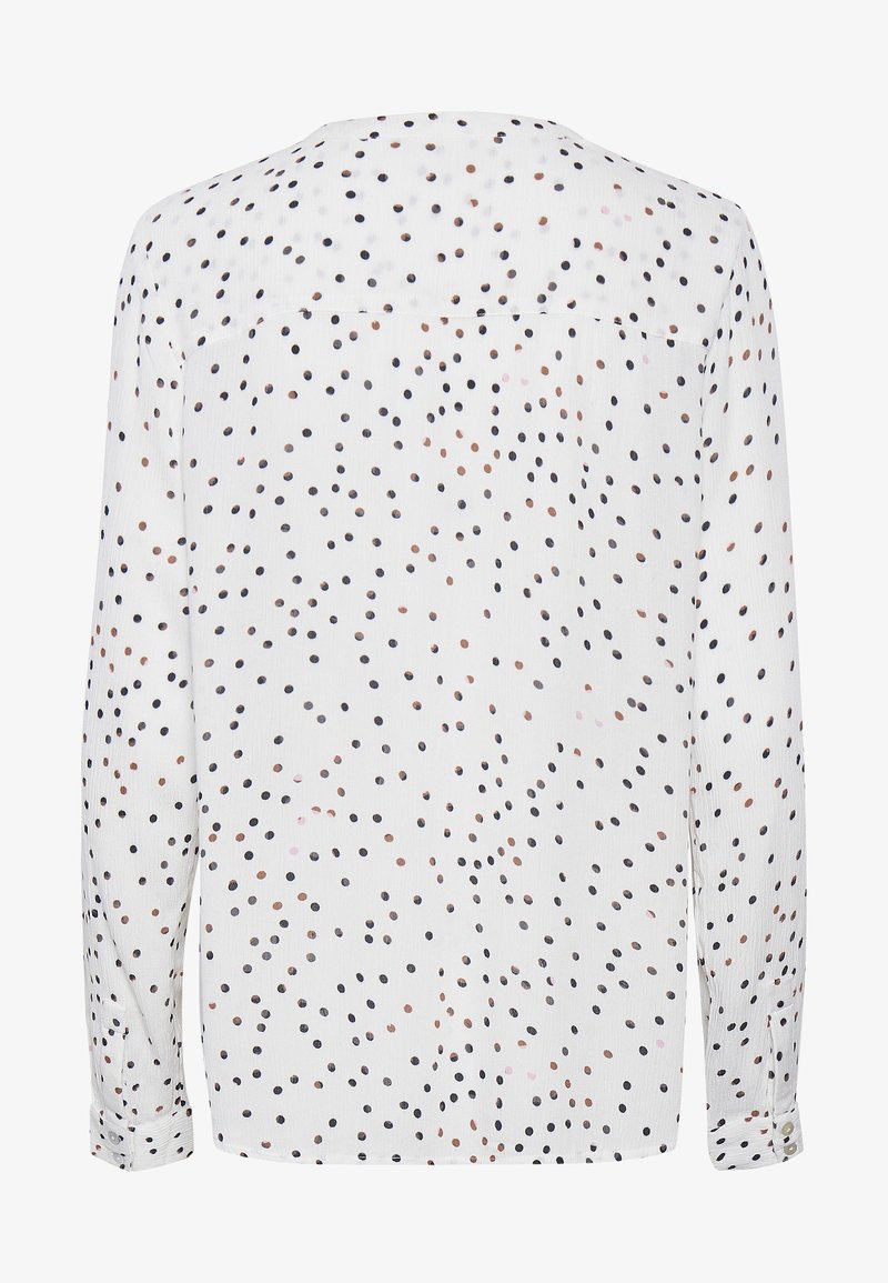 Blouse blanche à manches longues avec des pois noirs et marron dispersés, poignets boutonnés, vue de dos.