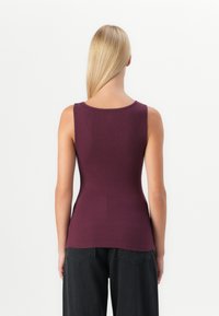 Burgundy sleeveless top made of stretchy fabric, featuring a round neckline and a fitted shape, back view showing smooth texture and silhouette.