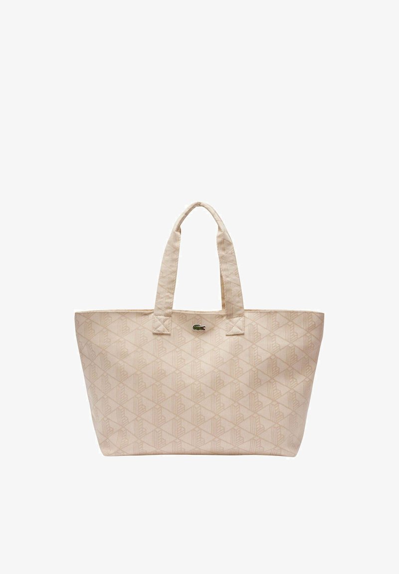 Beige tote bag with geometric pattern, two handles, and small green crocodile logo centered near the top.