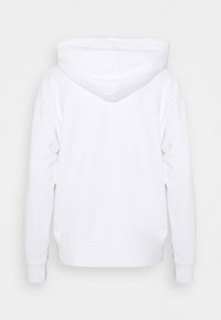Sweat à capuche blanc à manches longues, avec poignets et ceinture côtelés, montré de dos sur un fond uni gris clair.