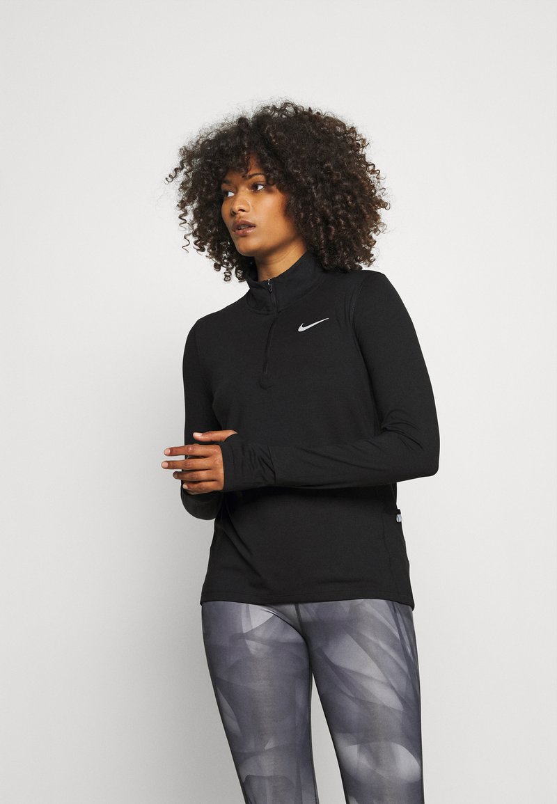 Black long-sleeve athletic top with a zip collar and reflective Nike logo. Paired with patterned gray leggings. Smooth, lightweight fabric.