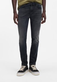 Tummanharmaat, kapealahkeiset farkut, joissa on viisi taskua, haalistunut pinta ja klassinen ompelu. Yhdistetty mustiin tennareihin, joissa on kermaiset nauhat.