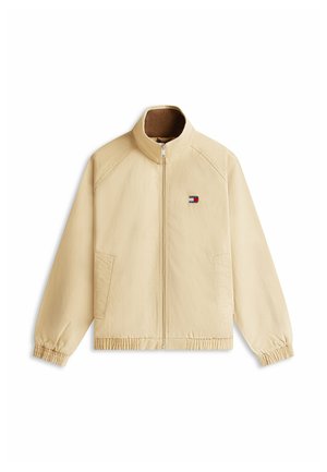 Beige Reißverschlussjacke mit Stehkragen, elastischen Bündchen und Saum, zwei Vorderentaschen sowie kleinem rot-weiß-blauem Logo auf der linken Brust.