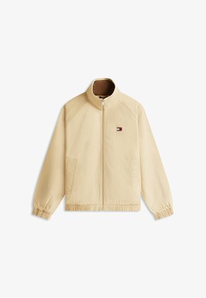 Beige Reißverschlussjacke mit Stehkragen, elastischen Bündchen und Saum, zwei Vorderentaschen sowie kleinem rot-weiß-blauem Logo auf der linken Brust.