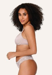 Set di lingerie rosa chiaro composto da un reggiseno morbido in tessuto liscio e mutandine rifinite in pizzo. La vista laterale mette in evidenza la forma e i dettagli.