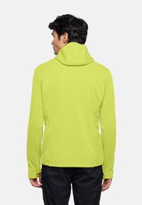 Giacca con cappuccio di un brillante verde lime, realizzata in tessuto morbido. Presenta maniche lunghe e un design aderente con cuciture laterali, senza hardware visibile.